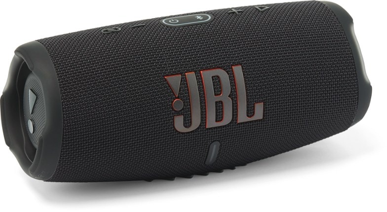 JBL Charge 5 waterproof Bluetooth speaker on a beach with waves in the background.