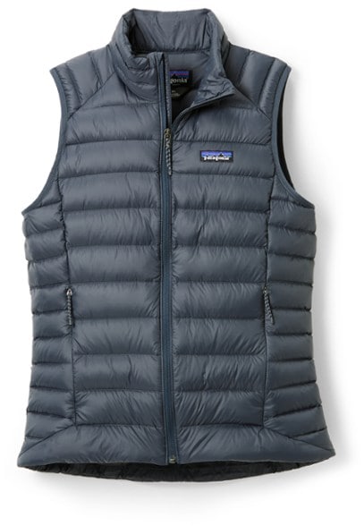 A woman hiking in the mountains wearing a lightweight down vest in navy blue