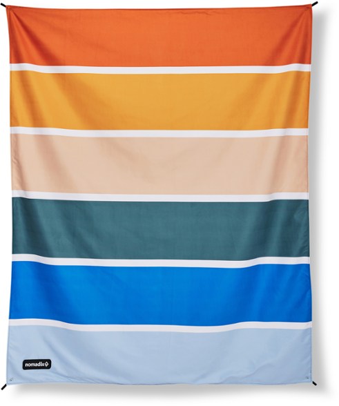 Nomadix Festival Blanket spread out on the beach, showcasing its slip-resistant surface.