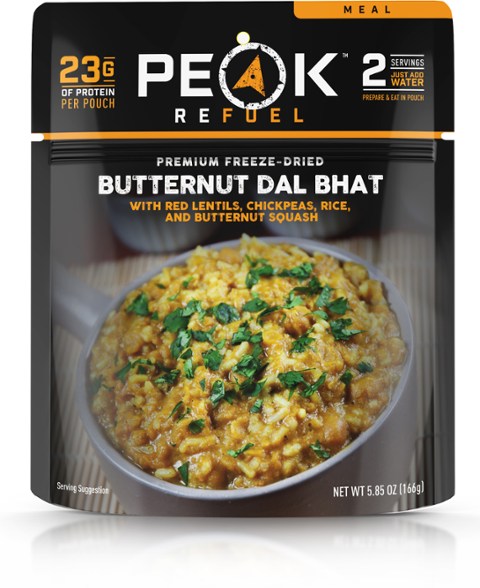 Angled view of Trail Spice Butternut Dal Kit pouch on a wooden camp table with hiking gear in background