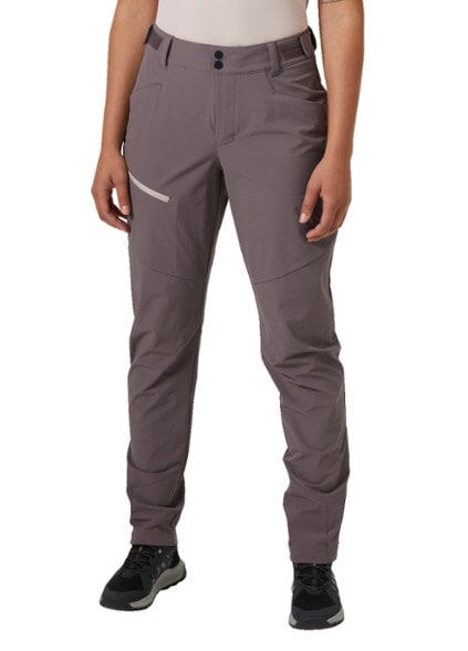 Blaze Women's Soft-Shell Hiking Pants in action on a rugged trail with vibrant nature background.