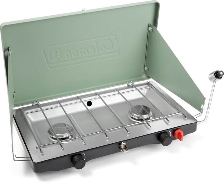 Angle view of the Cascade Classic camp stove in use outdoors, showcasing its two burners and wind guards.