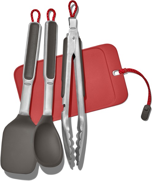 Camp stove cooking set displayed on a picnic table with utensils arranged neatly.