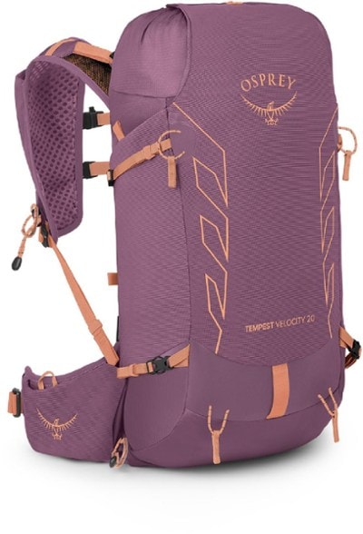 Osprey Tempest Velocity 20 backpack displayed on a rocky trail, showing flexible back panel and emergency whistle.