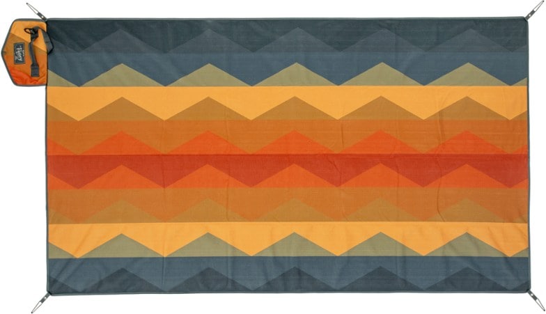 NEMO Eco Victory Blanket spread out on a sandy beach, showcasing its waterproof bottom and vibrant design.