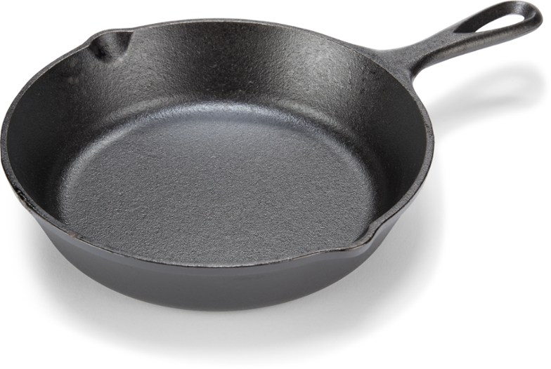 Overhead view of cast iron skillet with scrambled eggs on a rustic wood table