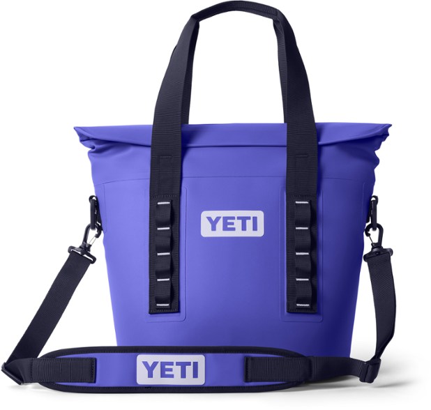 YETI Hopper M15 soft cooler opened on a rocky shoreline, showing internal storage and insulation
