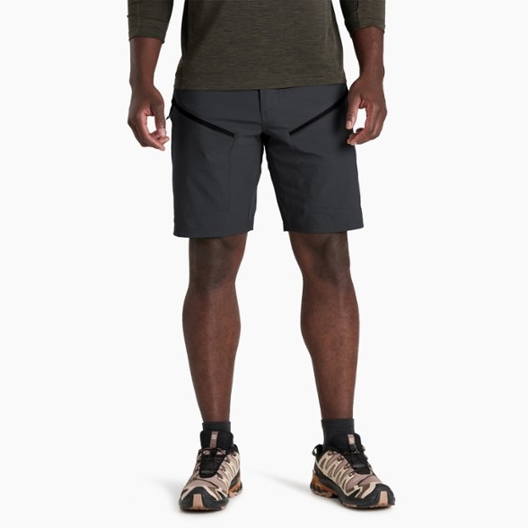 Front view of men's hiking shorts in motion on rocky trail, showcasing durable cargo pockets and quick dry fabric