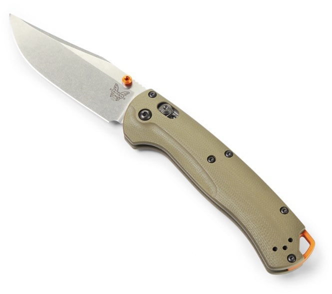 Benchmade Taggedout knife with OD Green G10 handle against a nature backdrop, highlighting its multipurpose features.