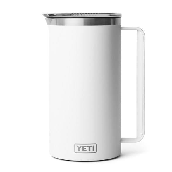 Side view of the YETI Rambler stainless steel pitcher on a table with drinks inside.
