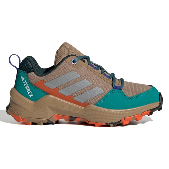 Side view of TrailBlazer AX4 Kids Boots on forest terrain, showcasing lace closure and rugged outsole