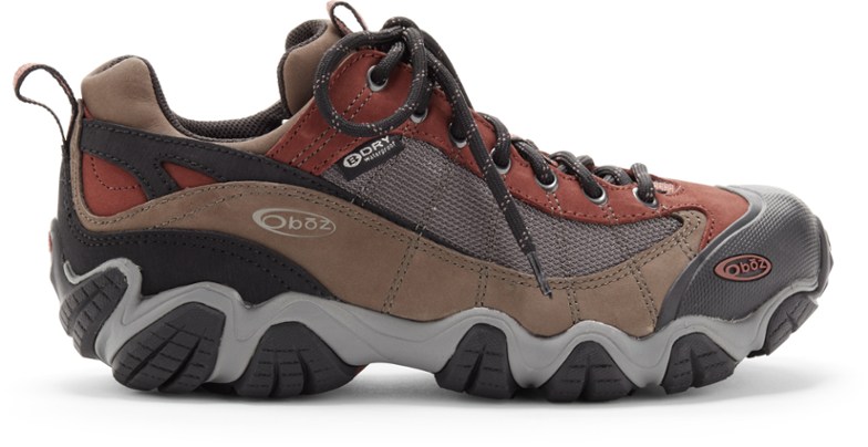Oboz Firebrand II hiking shoes in action on a muddy trail, showcasing waterproof capabilities.