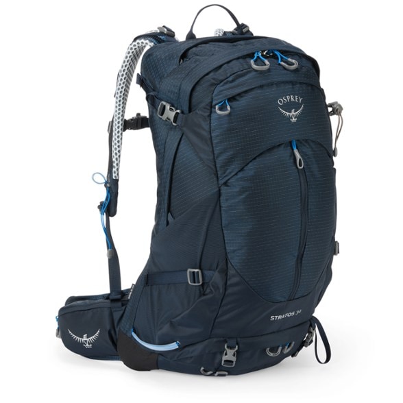 Osprey Stratos 34 backpack with hiking gear attached, showcasing its stow-on-the-go trekking pole attachment.