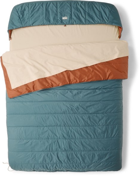 Top-down view of the double sleeping bag laid across a deluxe camping pad, showing the quilt and hood attached.