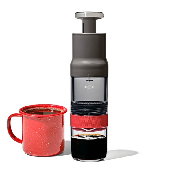 Eco-friendly portable coffee brewer in use at a campsite, showcasing its compact design.