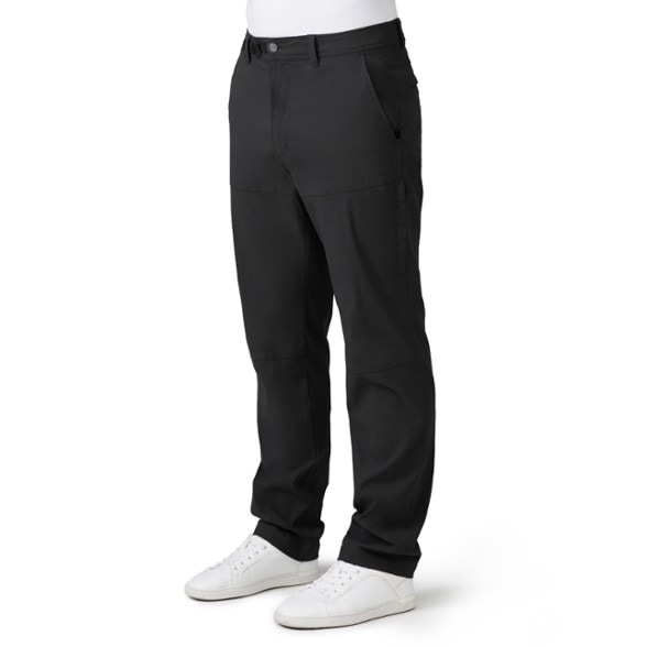 Men's Adventure Nylon Stretch Pants shown in a hiking setting, highlighting their water-repellent feature.