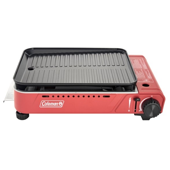 Xcursion portable butane grill set up at a campsite, showcasing its cooking surface.