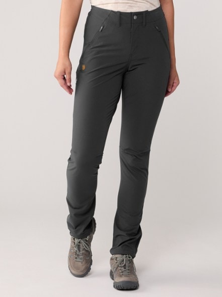 Eco-friendly women's stretch trekking pants shown on a hiking trail, highlighting zippered pockets.