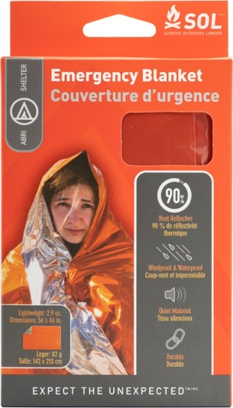 TrailGuard survival blanket laid out next to backpack in forest setting