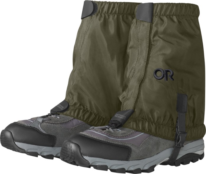 Close-up of durable hiking gaiters with insect shield strapped over hiking boots on rocky terrain