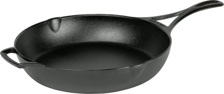 Lodge lightweight cast iron skillet on a campfire grill, perfect for outdoor cooking.