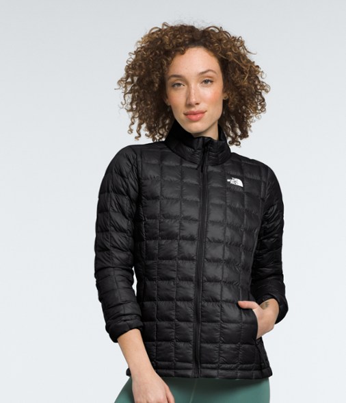 Eco-friendly women's ThermoBall insulated jacket in outdoor setting, showcasing its stylish design and water-resistant features.