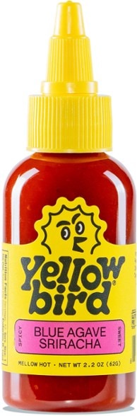 Close-up of Yellowbird Serrano hot sauce bottle with vibrant green label, showcasing fresh serrano peppers and natural ingredients