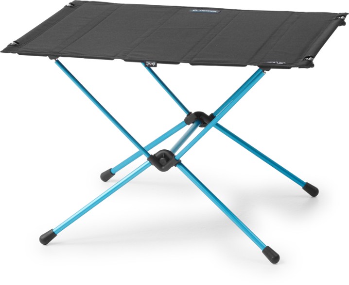 Helinox TrailMaster camping table set up next to a tent, showcasing durable outdoor furniture for camping trips
