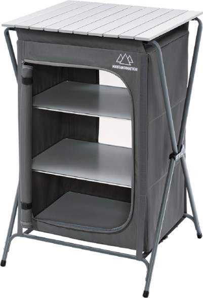 Angled view of the portable camping table set up outside a tent with ingredients and cooking gear stored neatly