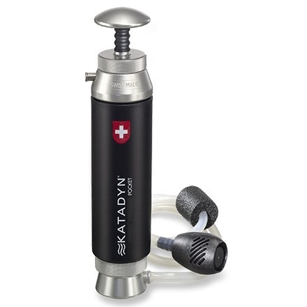 TrailGuard pump water filter shown in forest clearing beside backpacking gear