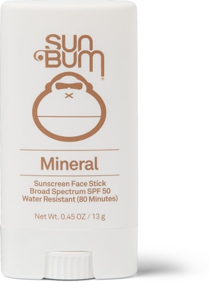 Close-up view of the PureShield SPF 50 mineral sunscreen stick resting on a beach towel under sunlight