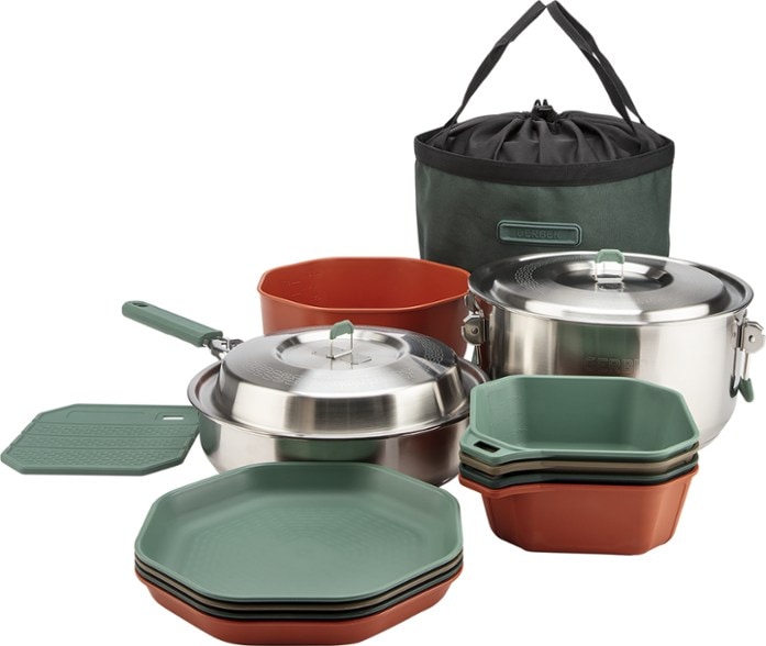 Stainless steel camping pots and pans arranged for a group meal outdoors.