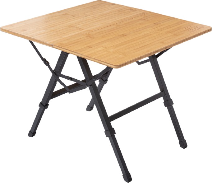 Overhead view of bamboo folding table set up on a backyard patio with picnic accessories
