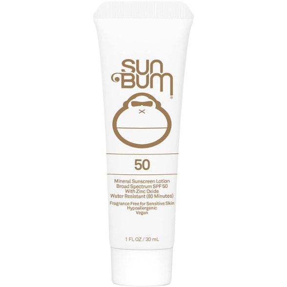Bottle of Sun Bum Vegan Mineral SPF 50 Sunscreen on a sandy beach, showcasing its water-resistant feature.