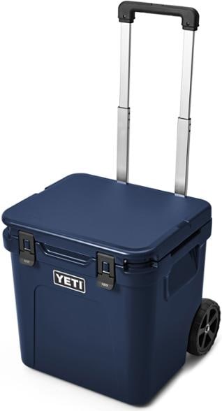 Front view of the YETI Roadie 48 wheeled cooler in a camping setting, highlighting its rugged wheels.