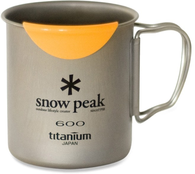 Snow Peak Ultralight Titanium 600 Mug displayed on a camping table with a stove in the background.